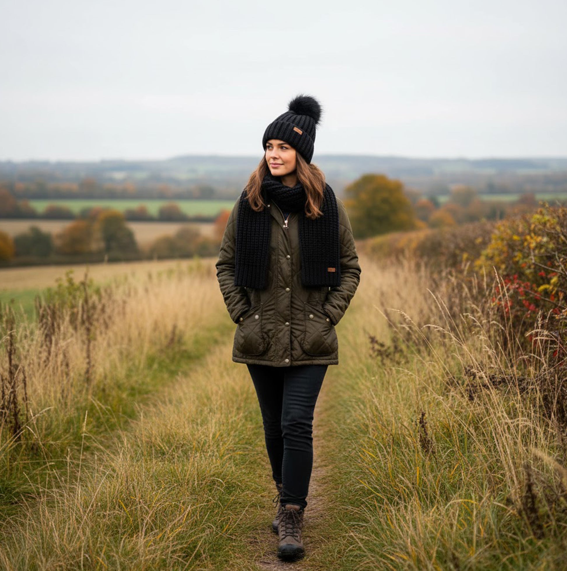 Barbour SALTBURN BEANIE & SCARF Womens Gift Set Black worn by a woman walking on a country path, showcasing the beanie and scarf.