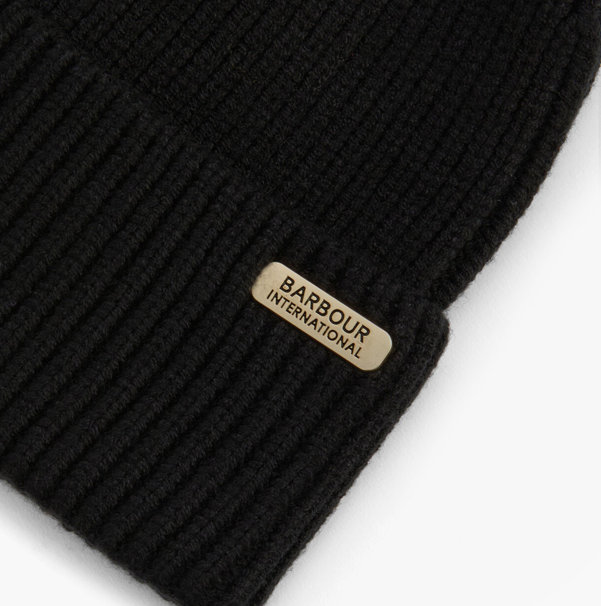 Barbour MALLORY POM Womens Beanie Black detail view showcasing the brand tag on a black knit beanie.