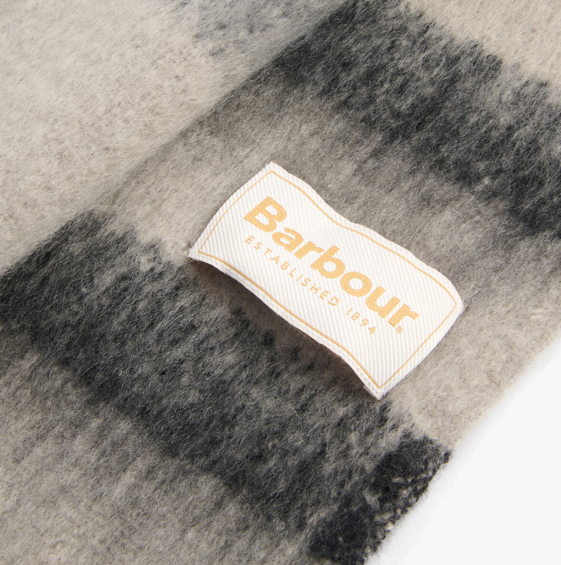 Barbour ISLA TARTAN BOUCLE Womens Winter Monochrome Tartan label detail view on soft fabric background.
