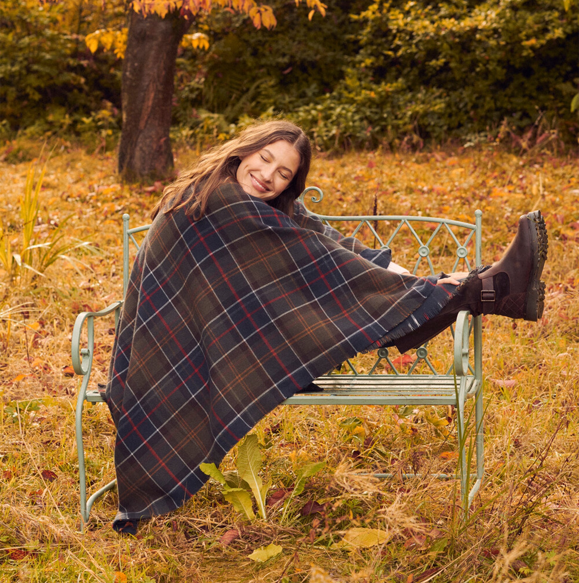Barbour MONTIETH SERAPE Womens Scarf Classic draped elegantly over a seated model, showcasing plaid design and fall colors.