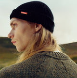 Barbour MOSELY Mens Fisherman Beanie Black side view, showcasing the ribbed material and removable metal Barbour pin.