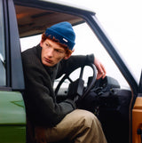Barbour MOSELY Mens Beanie Inky Blue worn by a man inside a vehicle, showcasing a side view of the beanie.