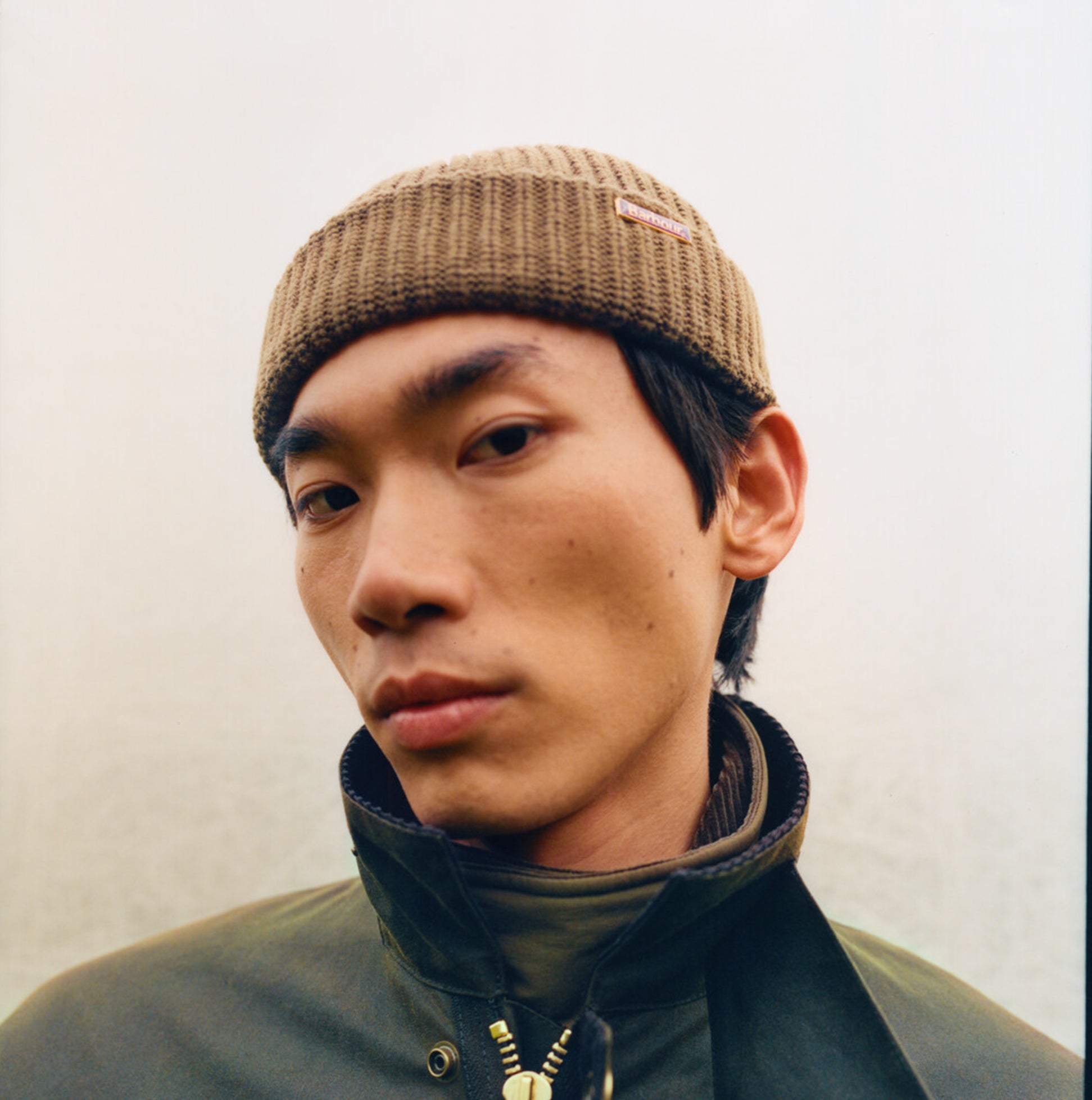 Barbour MOSELY Mens Fisherman Beanie Light Sage front view on model wearing a jacket, showcasing the hat's design.