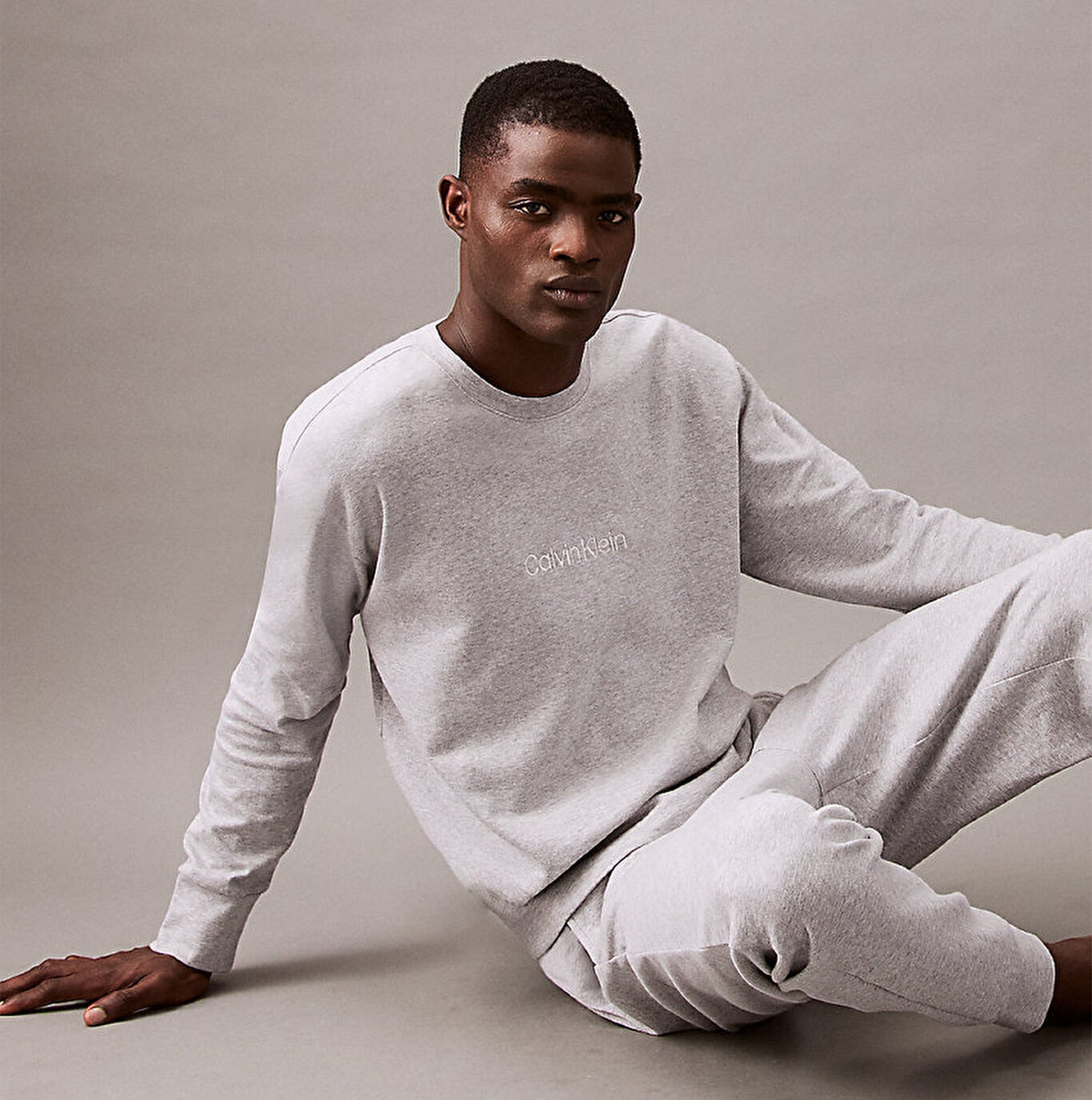 Calvin Klein ICON COTTON TERRY Mens Sweatshirt Medium Grey Heather front view worn by model sitting on the floor.
