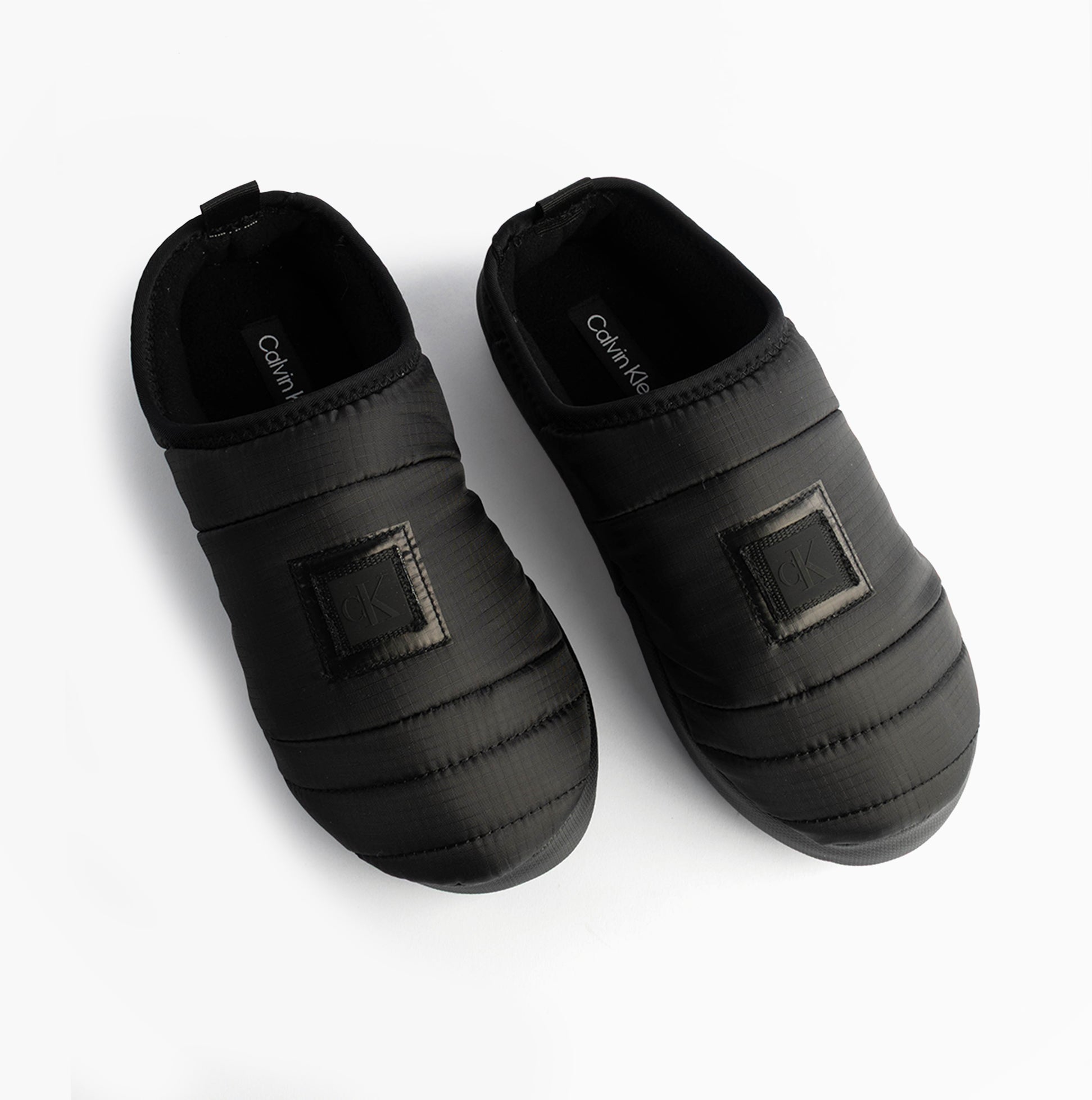 Calvin Klein HOME SLIPPER NYL PAT Womens Slippers Black top view showing soft polyester upper and slip-on design.