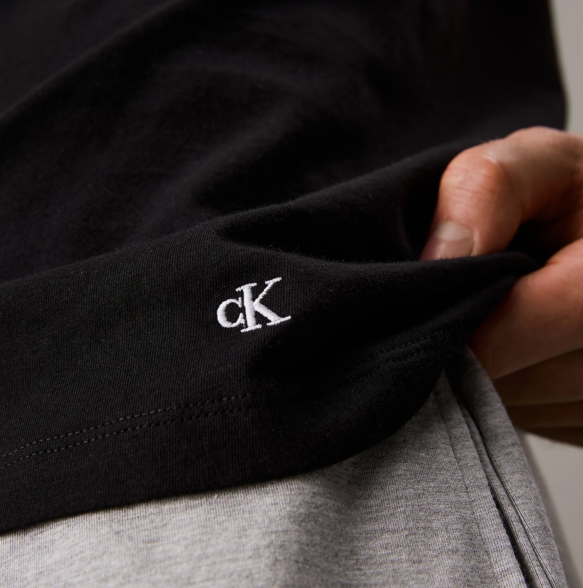 Calvin Klein 100% COTTON 3 Pack Mens T-Shirts Black/Grey Heather/White detail view of CK embroidery on black t-shirt.