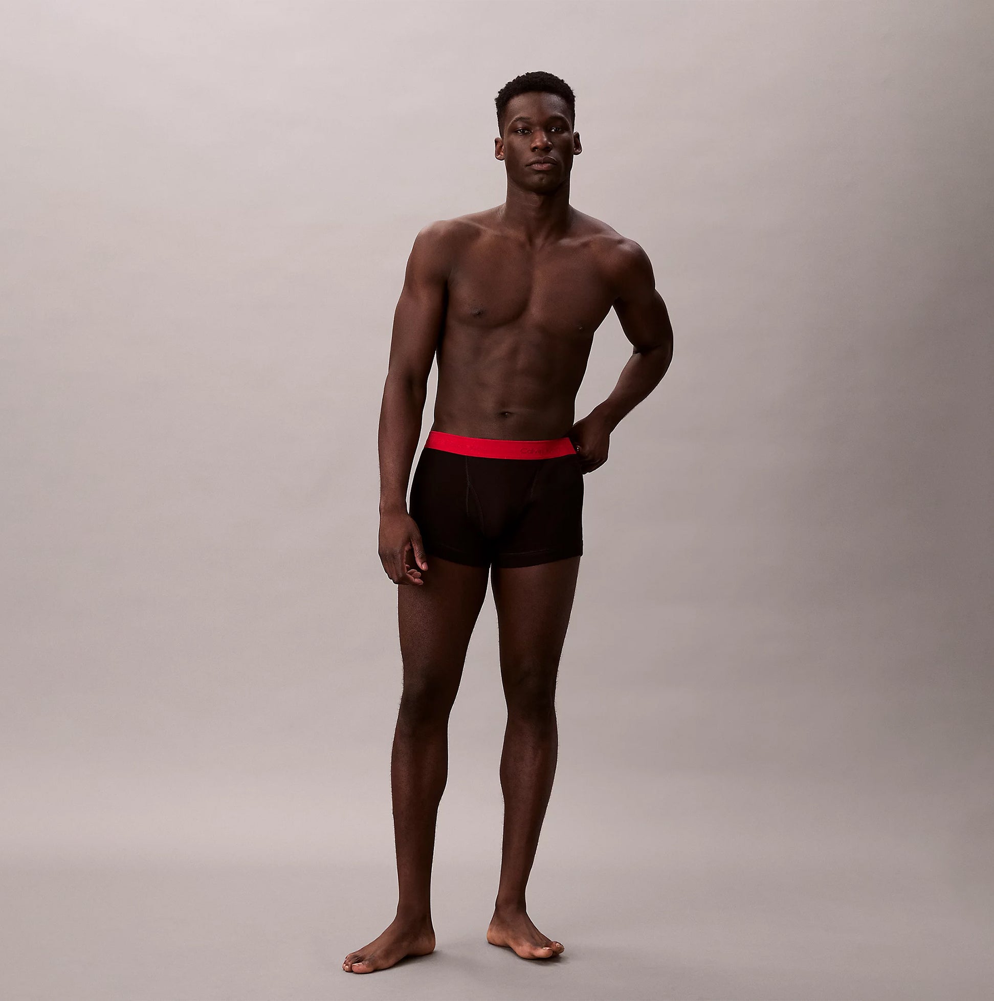 Calvin Klein TRUNK Mens 5 PACK Multicoloured front view of model wearing black trunk underwear with red waistband.