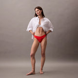 Calvin Klein THONG Womens Icon Logo Lace Molten Red worn by a model in a side view with a white shirt, showcasing the lace detail.