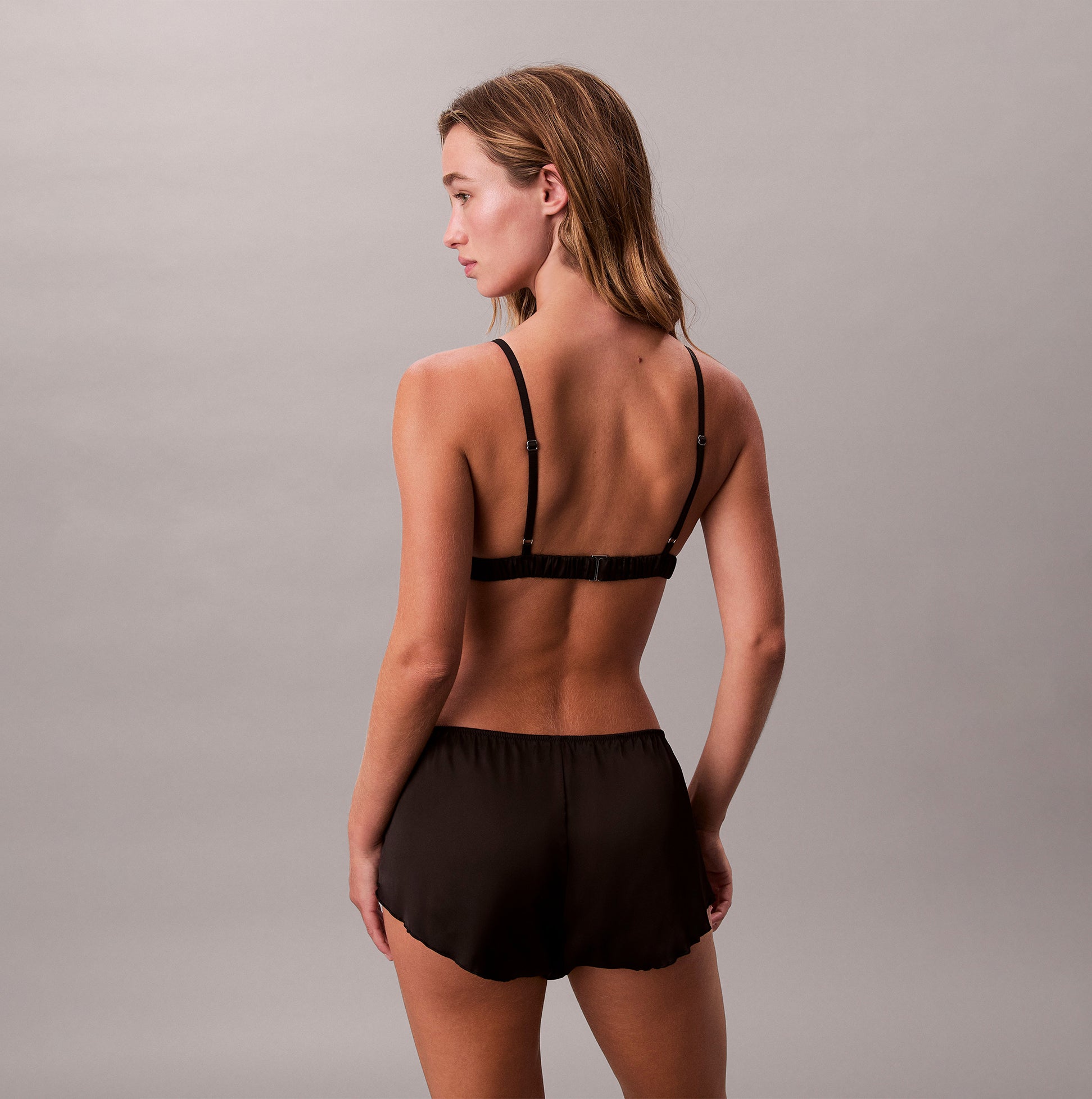 Calvin Klein UNLINED TRIANGLE Womens Black back view of the bra with matching black shorts, showcasing a sleek design.