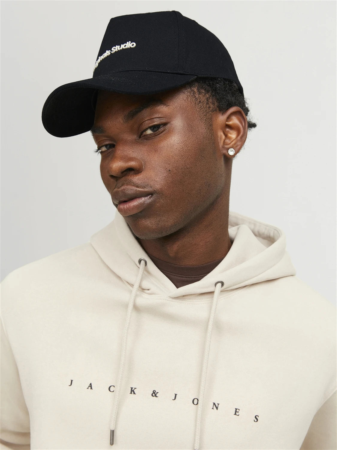 Jack & Jones VESTERBRO Mens Cap Black front view, model wearing cap with logo, style with neutral hoodie.