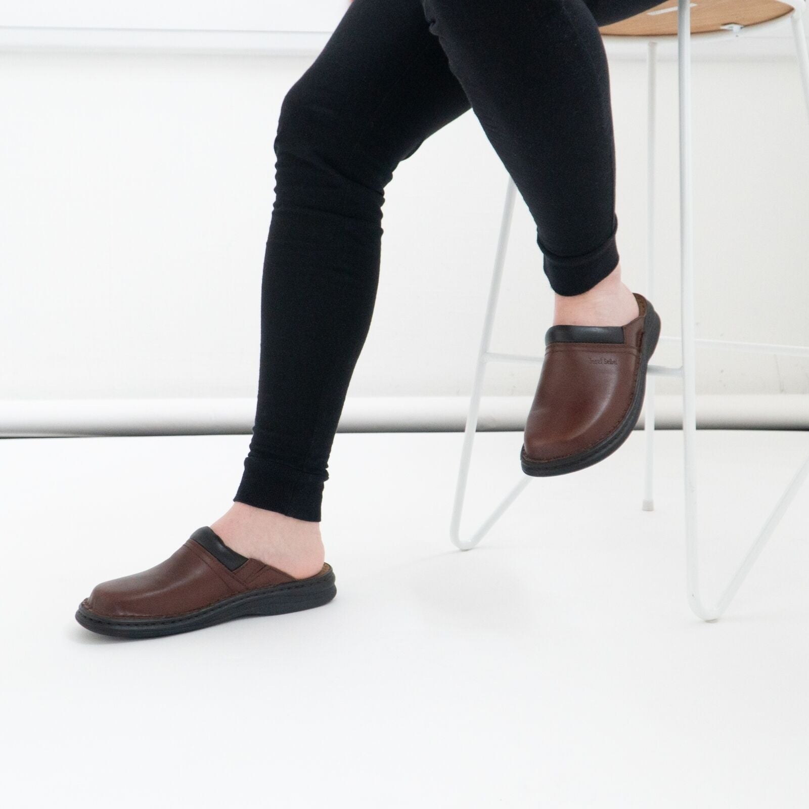 Josef Seibel MAX Mens Clogs Brandy side view worn on foot with black pants, showcasing slip-on design and brown leather.
