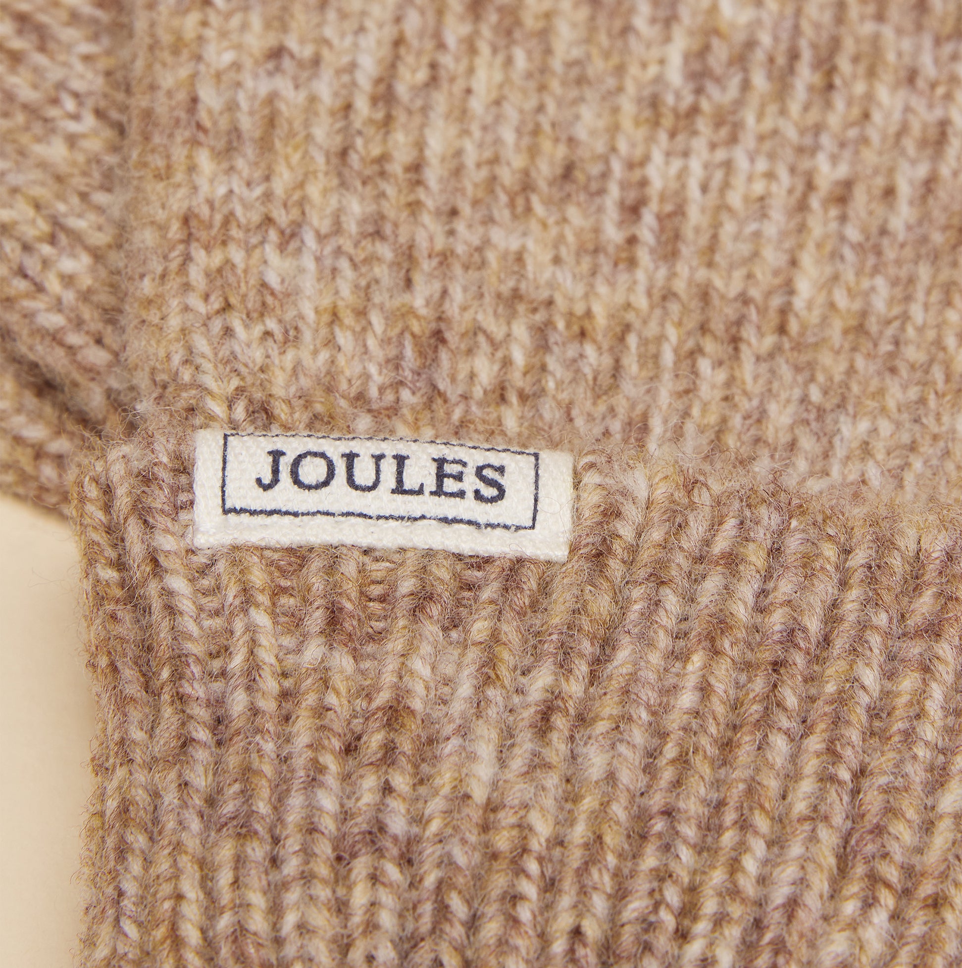 Joules ROSA Womens Gloves Oatmeal, detail view of the label showing brand Joules on textured oatmeal fabric.