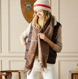 Joules LANGTREE Womens Scarf Tan Brown front view styled with brown vest and hat, showcasing its plaid design and fringe ends.