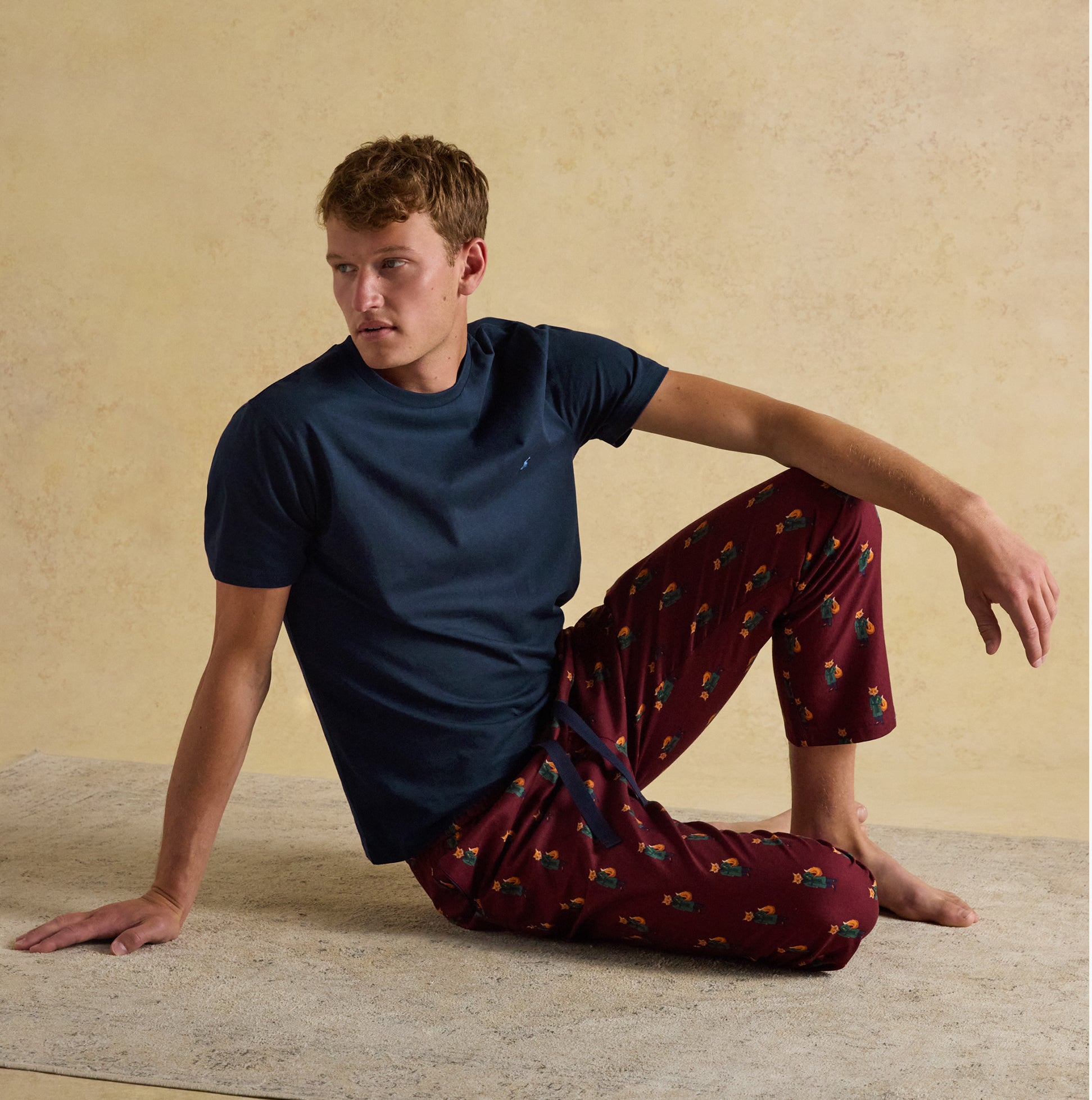 Joules DOZER Mens Pyjama Trousers Burgundy Red side view with model in relaxed fit, featuring cotton fabric and playful design.