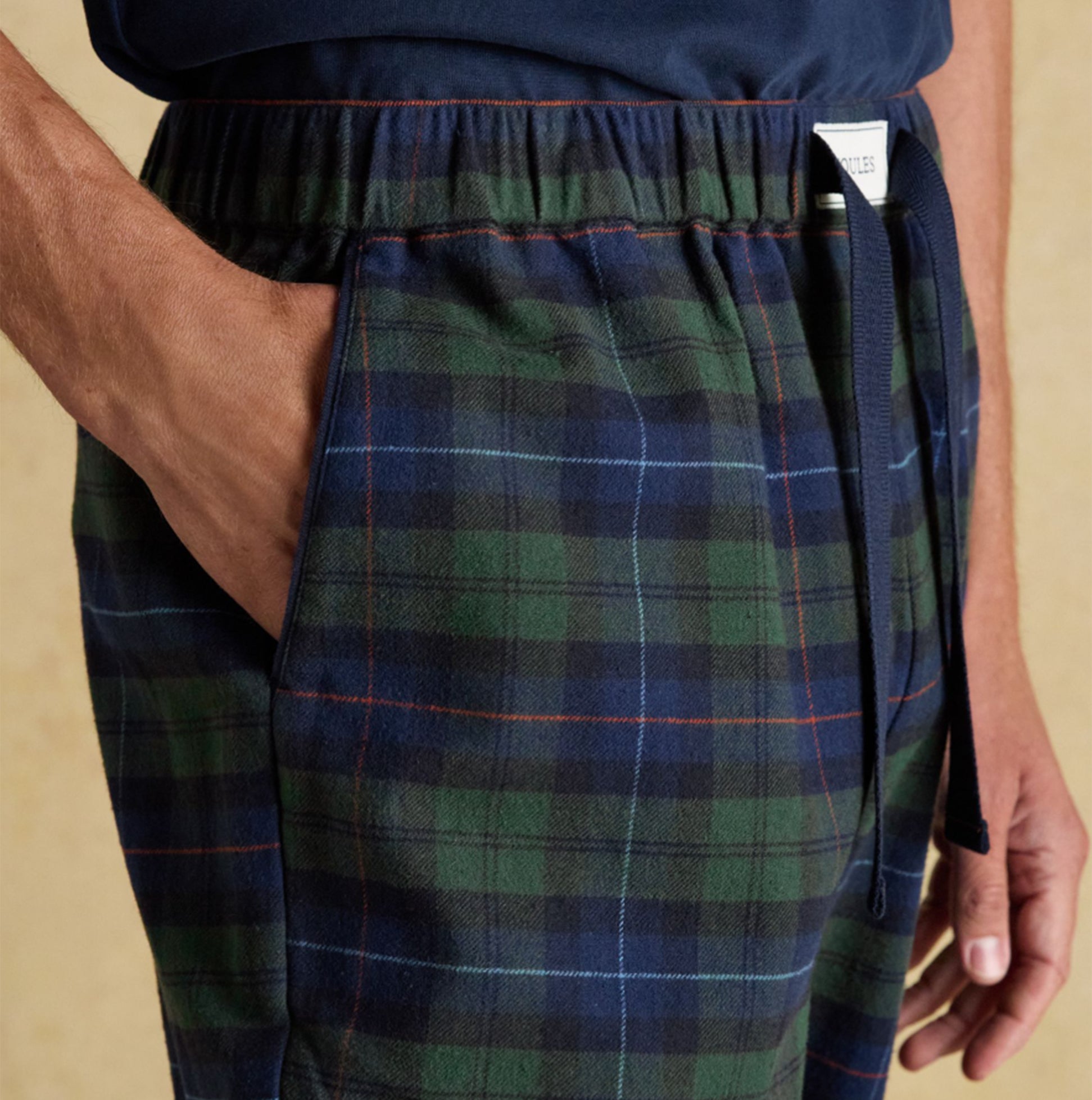 Joules DOZER Mens Pyjama Bottoms Green/Navy side view showcasing hand in pocket and relaxed fit fabric details.