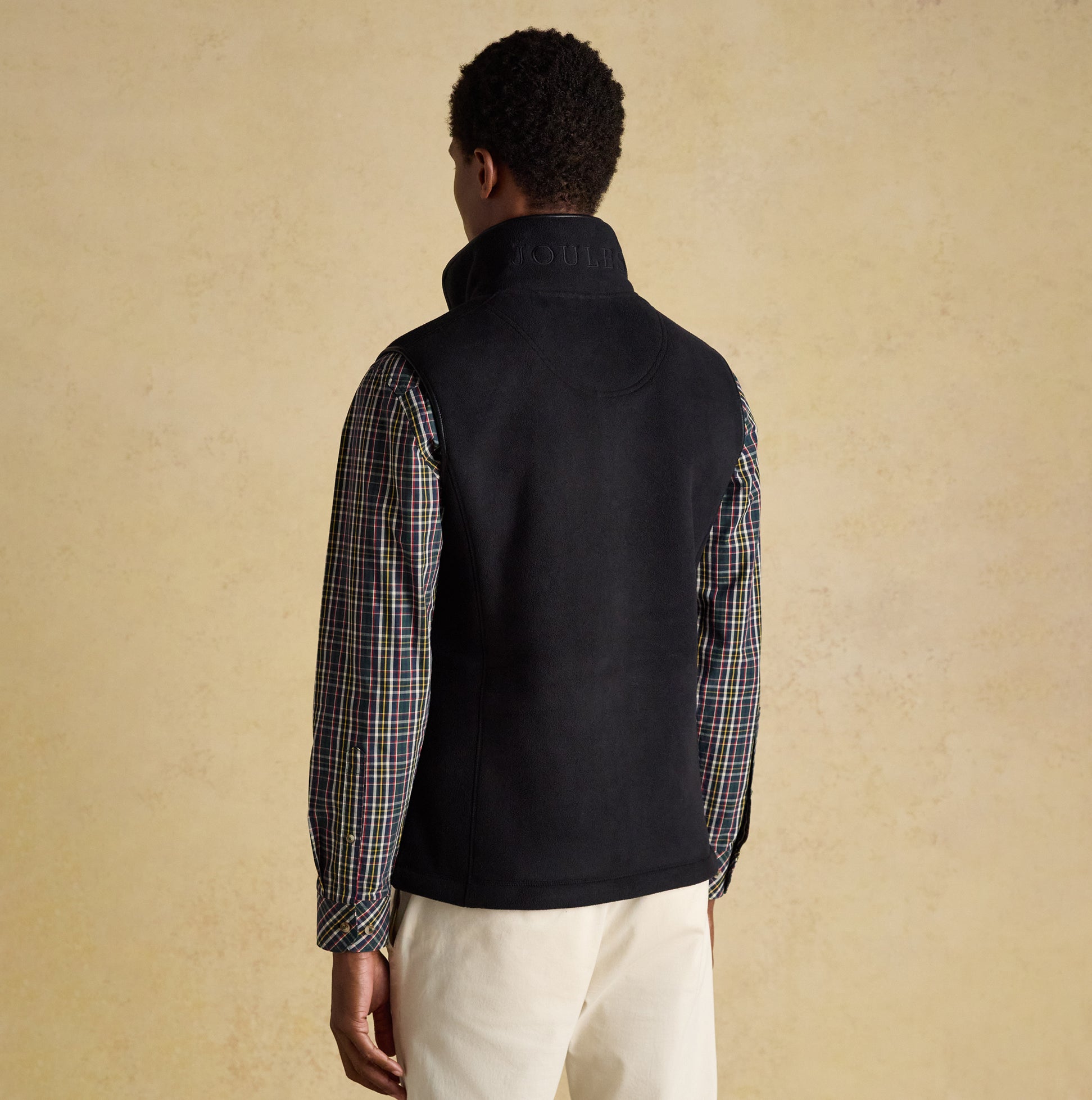 Joules HERITAGE FLEECE Mens Gilet Black back view worn over a plaid shirt, showcasing the collar and sleeveless design.