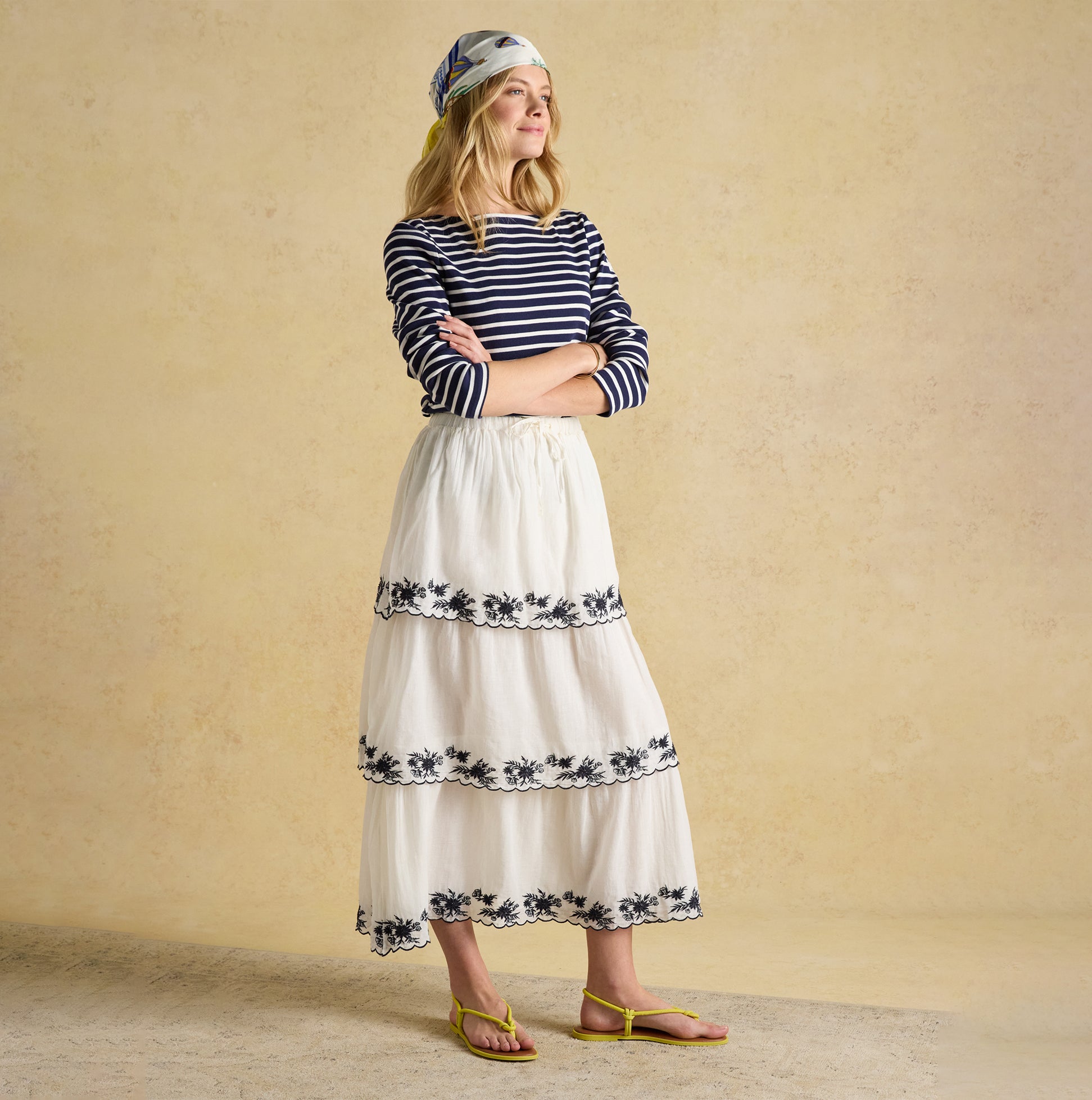 Joules HARBOUR Boat Neck 100% Cotton Breton Top Navy/White Stripe front view with white skirt and beach sandals.