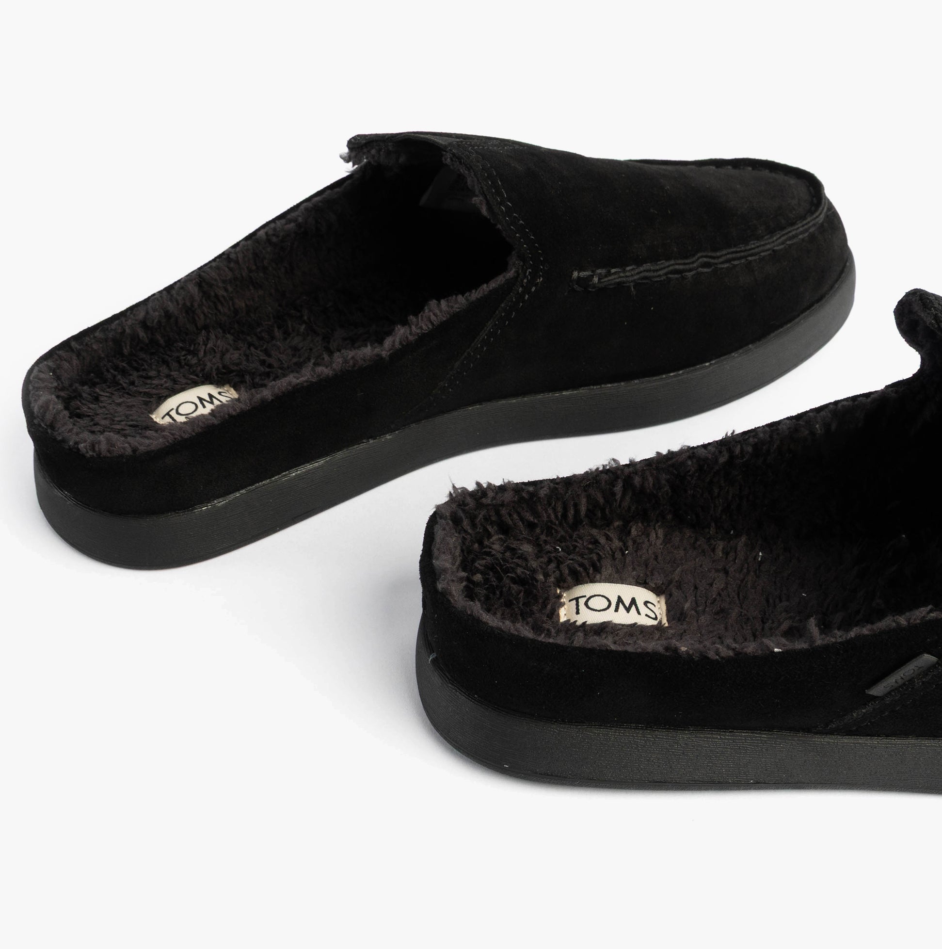 TOMS ALONSO MULE Mens Faux Shearling Lined Slippers Black side view showcasing suede leather and warm shearling lining.