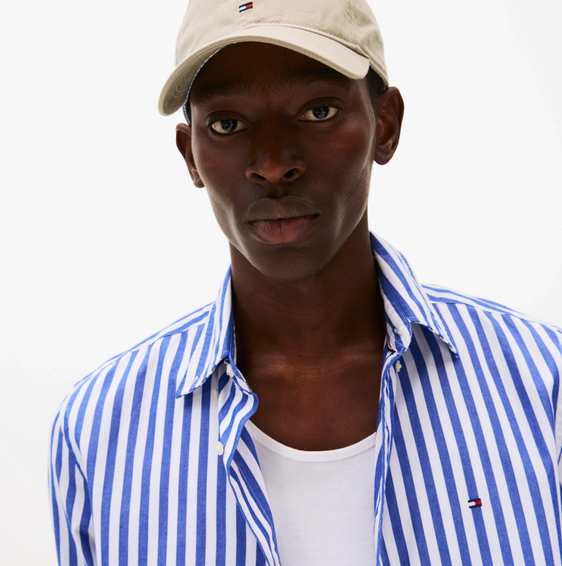 Tommy Hilfiger Flag Baseball Cap Sandalwood front view worn by model with striped shirt.