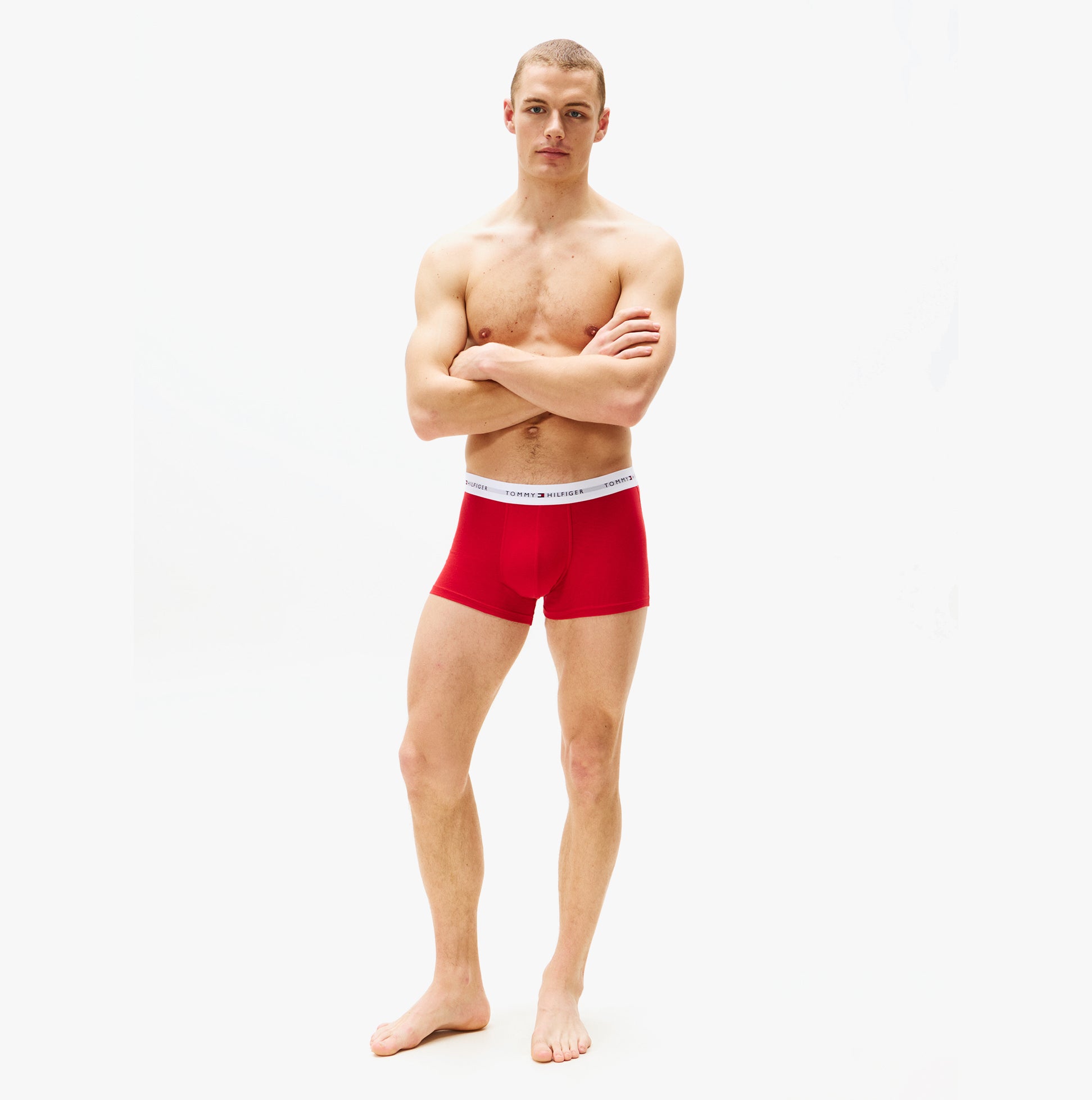 Tommy Hilfiger 3 Pack Trunk Mens Trunks Desert Sky/White/Primary Red side view of red trunk on model with arms crossed.