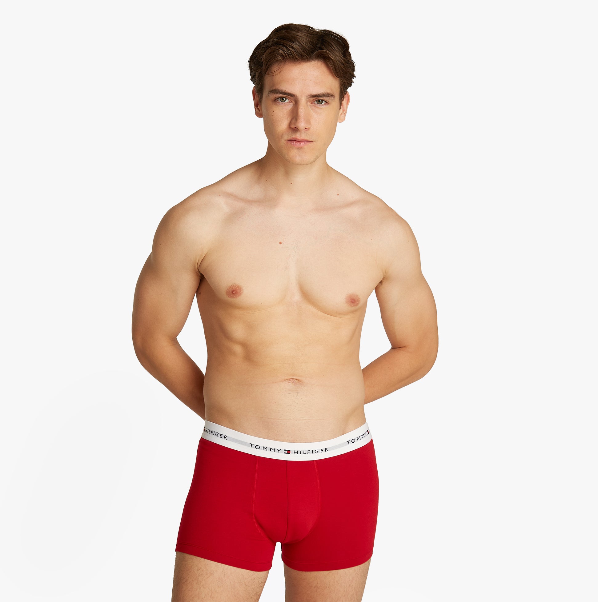 Tommy Hilfiger 3 Pack Mens Logo Waistband Trunks Multicoloured front view model wearing red trunks with TH logo waistband.