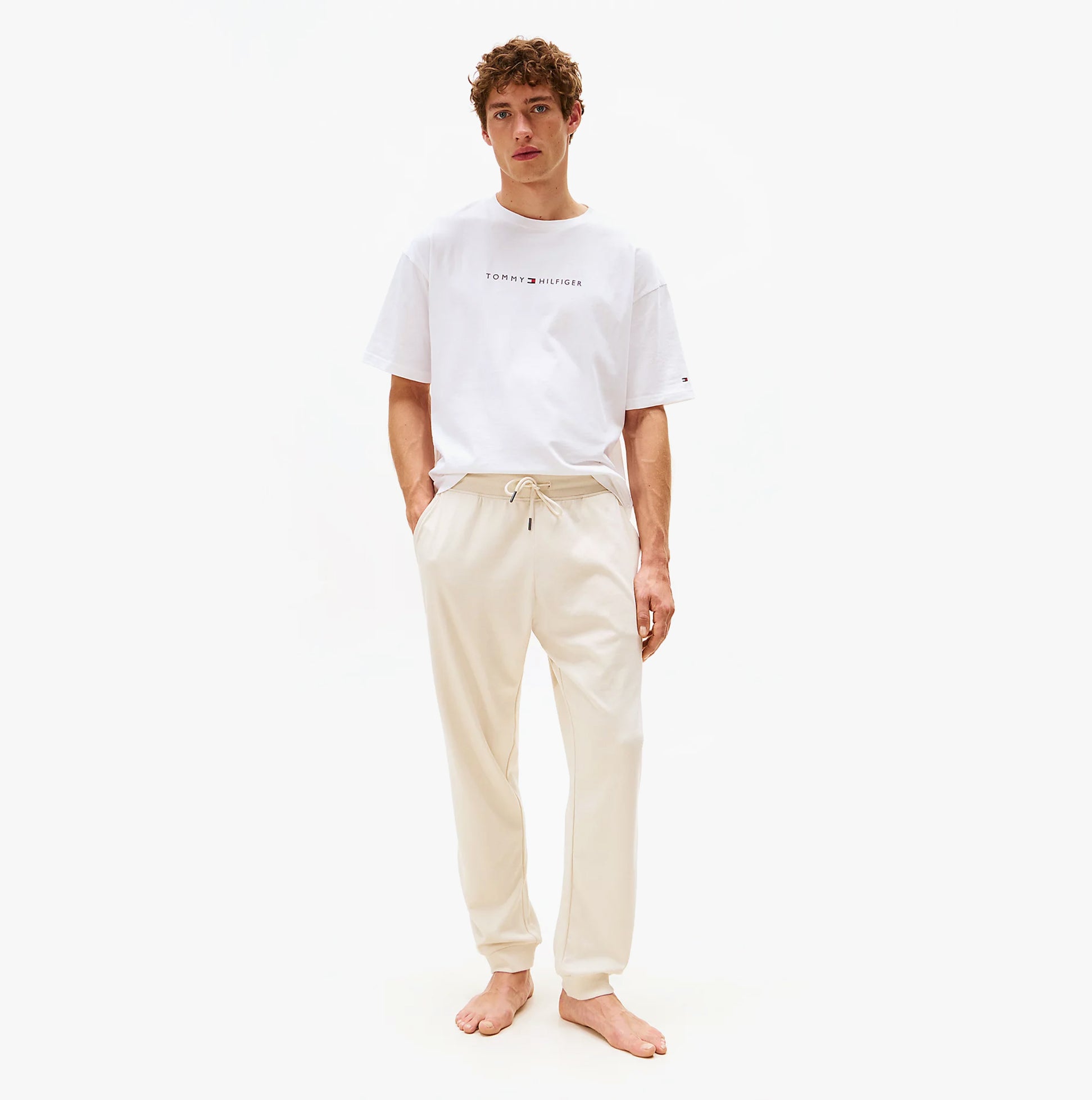 Tommy Hilfiger TH Original Mens Logo Lounge Joggers Off White Newsprint front view on model wearing a white shirt.