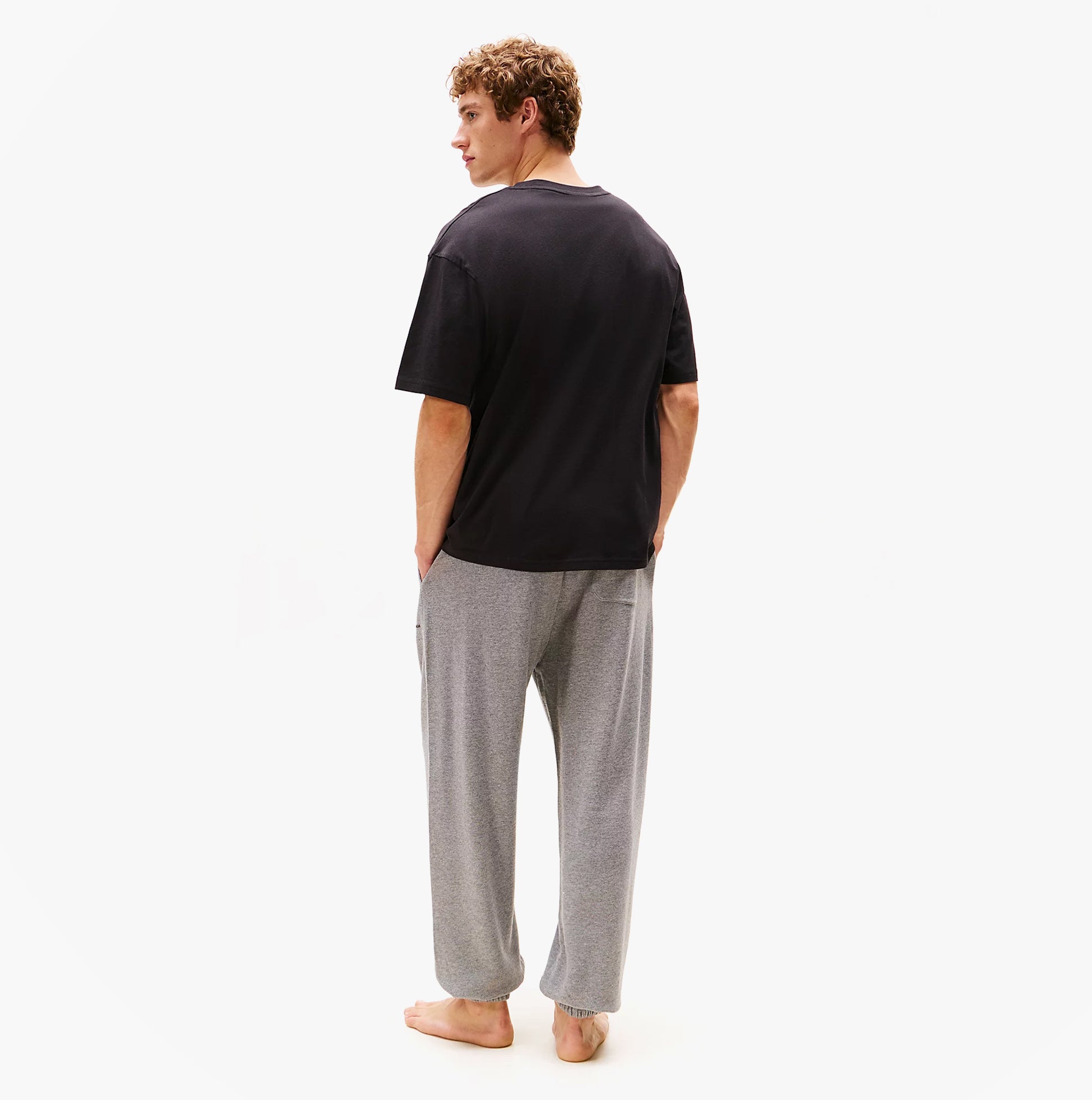 Tommy Hilfiger LOGO T-Shirt Mens Black back view on model wearing grey pants.