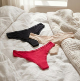 Tommy Hilfiger 3 PACK LACE Womens Thong Multicoloured, front view of black, beige, and red thongs on bed.