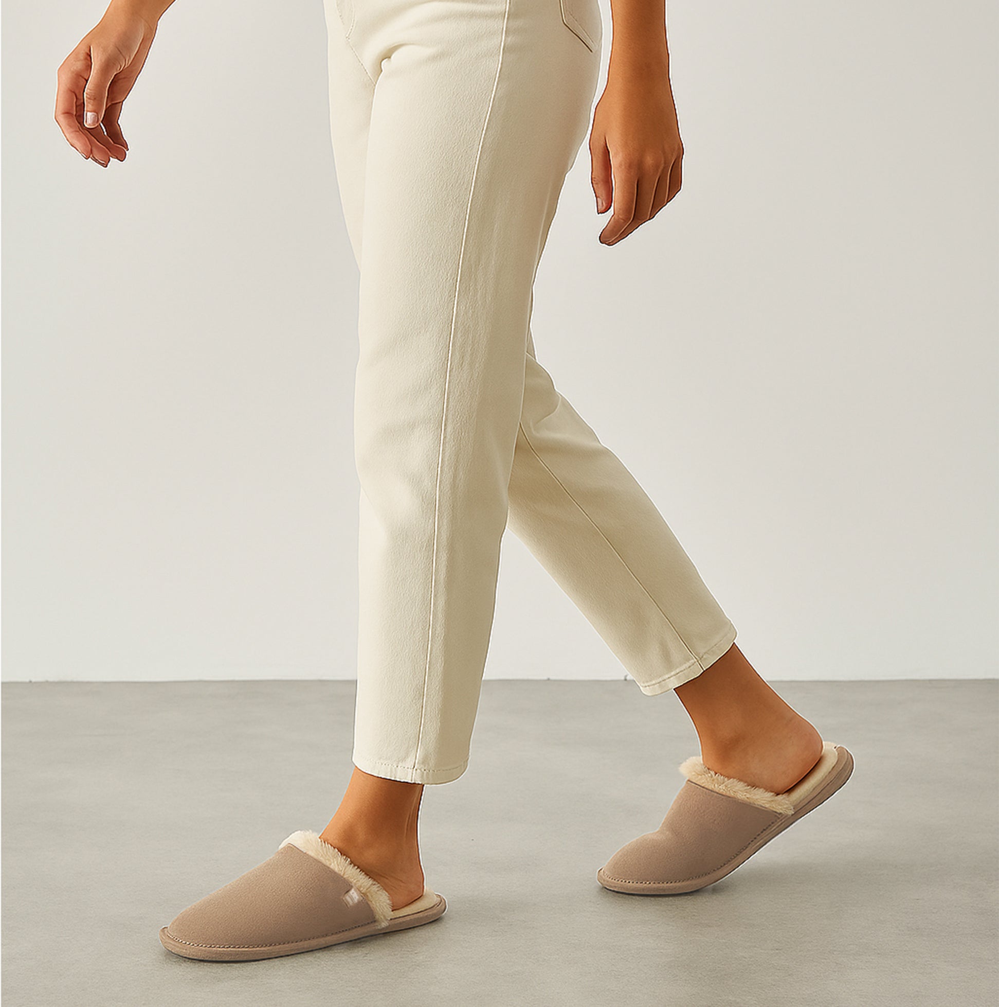 Totes Isotoner REAL SUEDE MULE Womens Slippers Sand side view on model wearing cream pants.