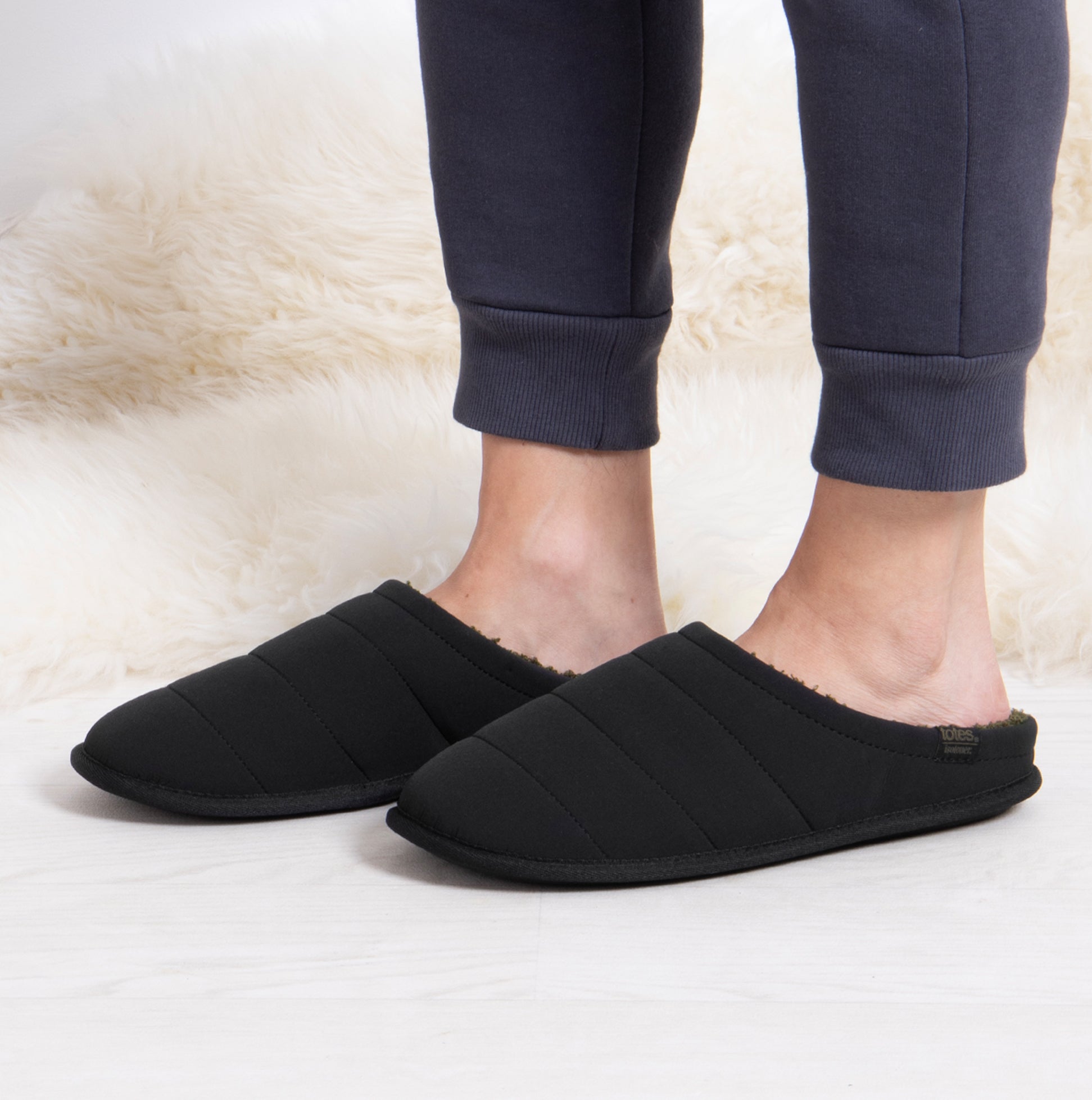 Totes Isotoner SPORT QUILTED MULE WITH COSY LINING Mens Mule Slippers Black side view worn with comfortable pants