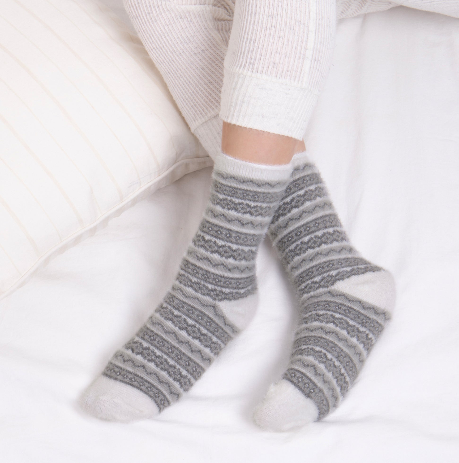 Totes Toasties FAIR ISLE Chenille Womens Socks Grey side view on a model's feet, styled with cozy bedding.
