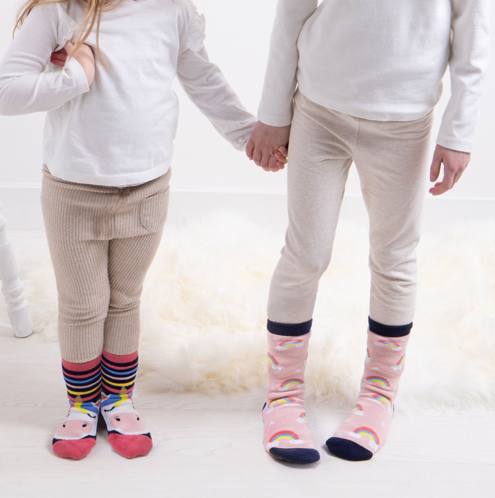 Totes Toasties ORIGINAL Slipper Socks (Twin Pack) Unisex Kids Socks Unicorn, front view of kids wearing colorful socks, holding hands.