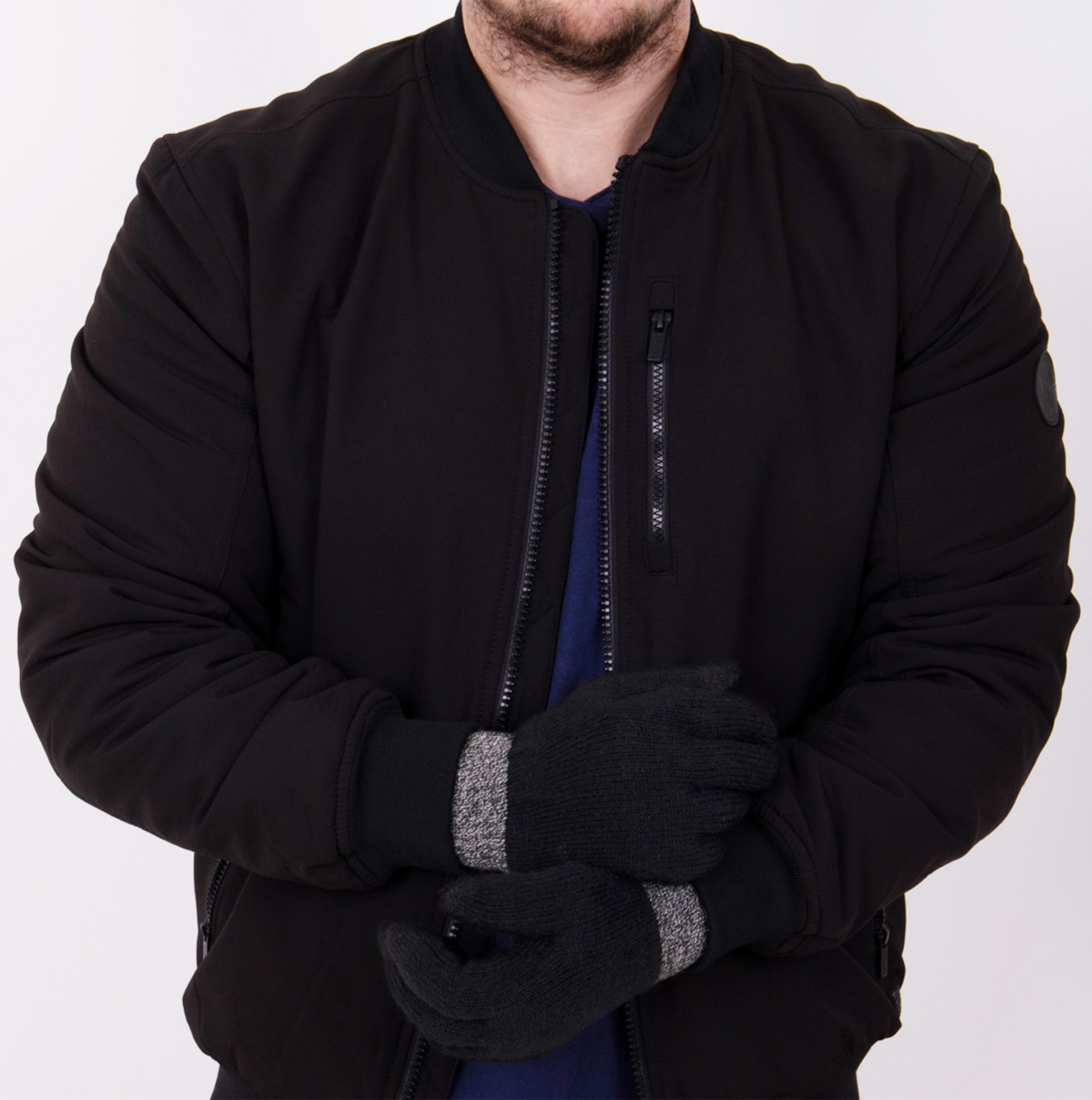 Totes Toasties STRETCH KNITTED SMARTOUCH Mens Gloves Black on model wearing black bomber jacket, front view, showcasing glove design.